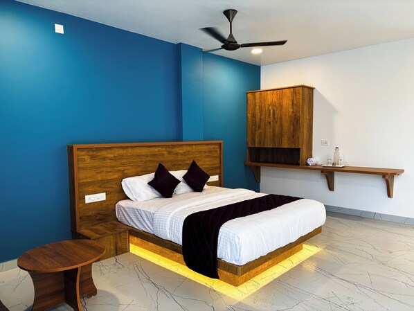 Une chambre à coucher avec un lit en bois, une table de chevet, un ventilateur de plafond et une armoire en bois.