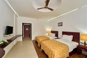 A hotel room with two beds, a TV, a desk, and a ceiling fan. - NO 18 HOTEL (Kochi)