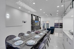 A modern dining area with a long table set for six, surrounded by chairs.