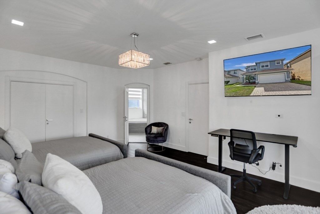 A modern bedroom with a bed, two bedside tables, a desk, and a chair.
