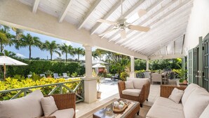 A covered outdoor seating area with wicker furniture, a ceiling fan, and a view of the surrounding greenery. - Gibbs Glade Villa 4 Bedroom Home by Bluescape (Gibbes)