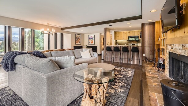 A modern living room with a gray sofa, a glass coffee table, and a fireplace. - 1776 Decatur 4 Bedroom Condo (Keystone)