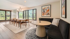A modern living room with a dining area, large windows, and artwork on the walls. - 1776 Decatur 4 Bedroom Condo (Keystone)