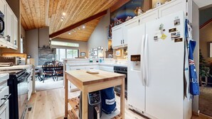 A modern kitchen with a wooden ceiling, white cabinetry, and a built-in dishwasher. - Snowcreek Iv #545 3 Bedroom Condo (Mammoth Lakes)