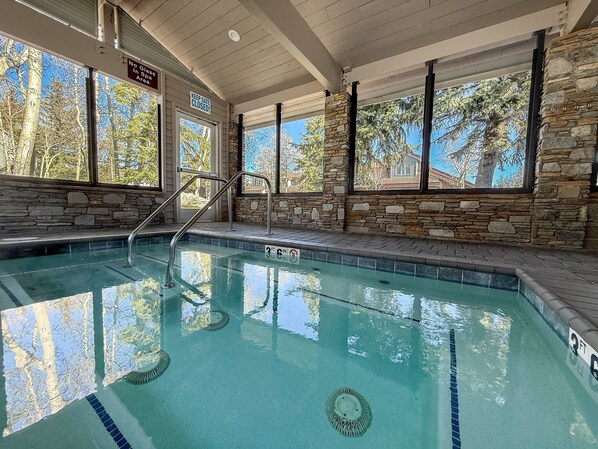 An indoor swimming pool with clear water, stone walls, and large windows. - Snowcreek Iv #545 3 Bedroom Condo (Mammoth Lakes)