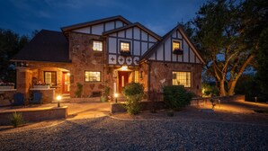 A two-story stone house with a prominent entrance, stone steps, and a gravel driveway. - The Beatrice Estate 7 Bedroom Estate (Grand Junction)