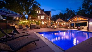 A swimming pool with lounge chairs, a covered patio area, and a large house with a chimney. - The Beatrice Estate 7 Bedroom Estate (Grand Junction)