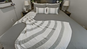 A neatly made bed with a striped blanket, two bedside lamps, and a clock on the nightstand. - The Loft Of Historic Charm 1 Bedroom Condo (Grand Junction)