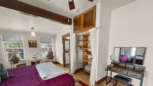 Een slaapkamer met een groot bed, een bureau met spiegel en een kledingkast.