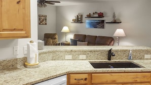 A kitchen with wooden cabinets, a white dishwasher, granite countertops, and a ceiling fan. - Hermosa Haven 3 Bedroom Home (Montrose)