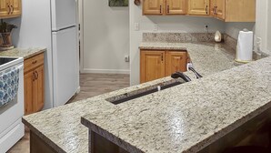 A kitchen with wooden cabinets, a granite countertop, a built-in oven, and a refrigerator. - Hermosa Haven 3 Bedroom Home (Montrose)