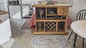 Una cucina compatta con mobili bianchi, un forno a microonde e un tavolo in legno con tovaglia a quadretti rossi e bianchi.