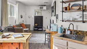 Una cucina compatta con isola in legno, lavello incassato e zona pranzo con divano e sedie.