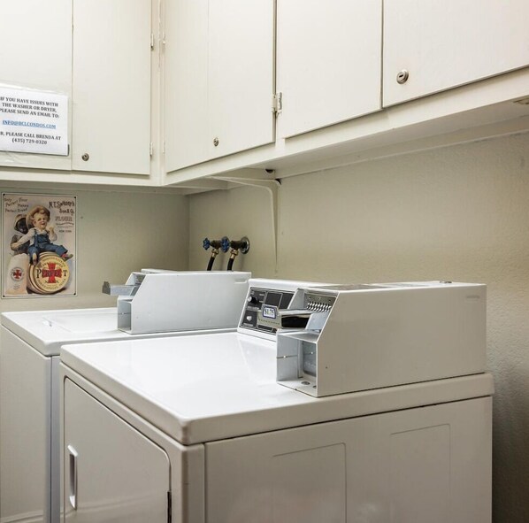 A laundry room with two washing machines, a water heater, and a poster on the wall. - Blue Church Lodge G 2 Bedroom Condo (Park City)