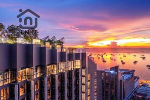 A modern hotel with a rooftop terrace overlooking a sunset over a body of water. - EDGE Central Pattaya By INH Global (Pattaya)