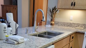 A modern kitchen with a built-in dishwasher, wooden cabinets, and a granite countertop. - Snowcreek Resort Vacation Rental 879 (Mammoth Lakes)