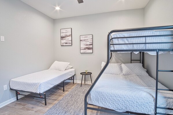 A bedroom with two bunk beds, a small round table with a plant, and two abstract wall art pieces.