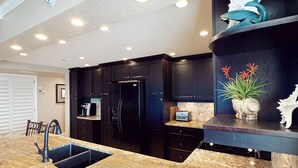 A modern kitchen with dark cabinetry, a granite countertop, and a built-in dishwasher.