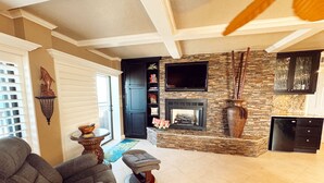 A living room with a fireplace, a television, and a dining area.