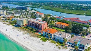 An aerial view of a coastal resort with beachfront properties, a river, and surrounding greenery.