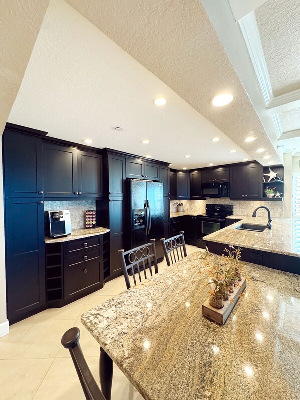 Una cocina moderna con gabinetes oscuros, encimera de granito y una isla central con asientos.