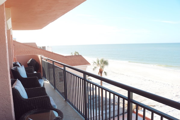 Ein Balkon mit Korbmöbeln mit Blick auf einen Strand.