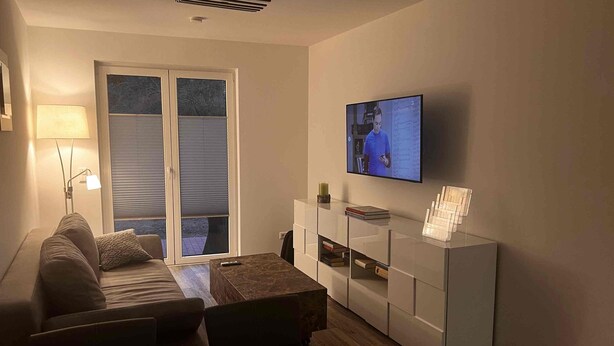 Een moderne woonkamer met een bank, salontafel en tv aan de wand.