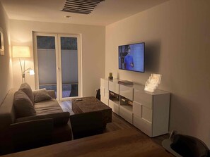 A modern living room with a sofa, coffee table, and TV mounted on the wall. - NEW - Exclusive hideaway on Lake Plessow (Werder (Havel))