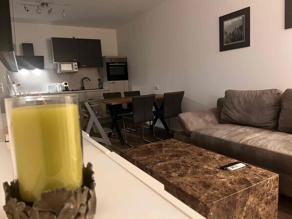 Ein modernes Wohnzimmer mit Sofa, Couchtisch und einem Essbereich mit Stühlen und Tisch.