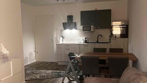 Een moderne woonkamer met een bank, een salontafel, en een eethoek met stoelen en een tafel.