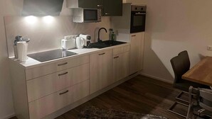 Een kleine keuken met een magnetron, broodrooster, waterkoker en oven.