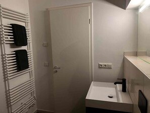 Ein Badezimmer mit einem weißen Waschbecken, einem Handtuchhalter und einer Tür.