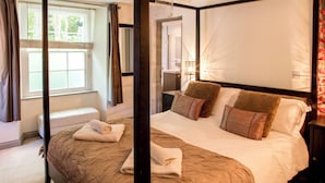 A four-poster bed with a canopy, a bedside table, and a nightstand. - Large home. Close to Beach, all en-suite bedrooms. Peaceful Wooded valley views (St Agnes)