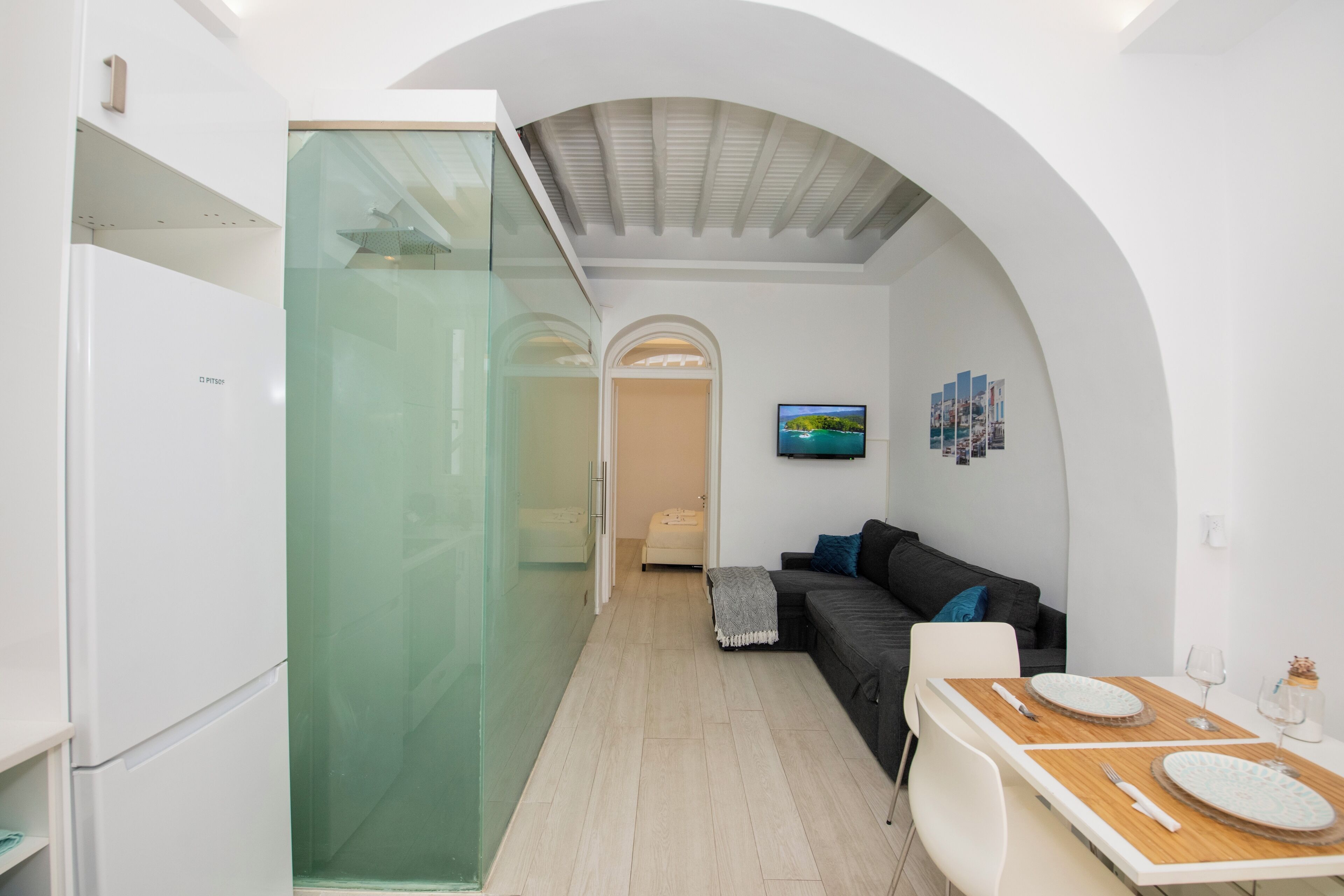 Un espai vital modern i compacte, amb zona de menjador, sofà i una separació de vidre.