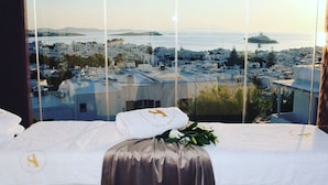 Ein Hotelzimmer mit einem großen Fenster und Blick auf eine Küstenstadt.