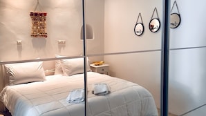 Ein modernes Schlafzimmer mit einem großen Bett, einem Nachttisch mit einer Schale und Wanddekoration.