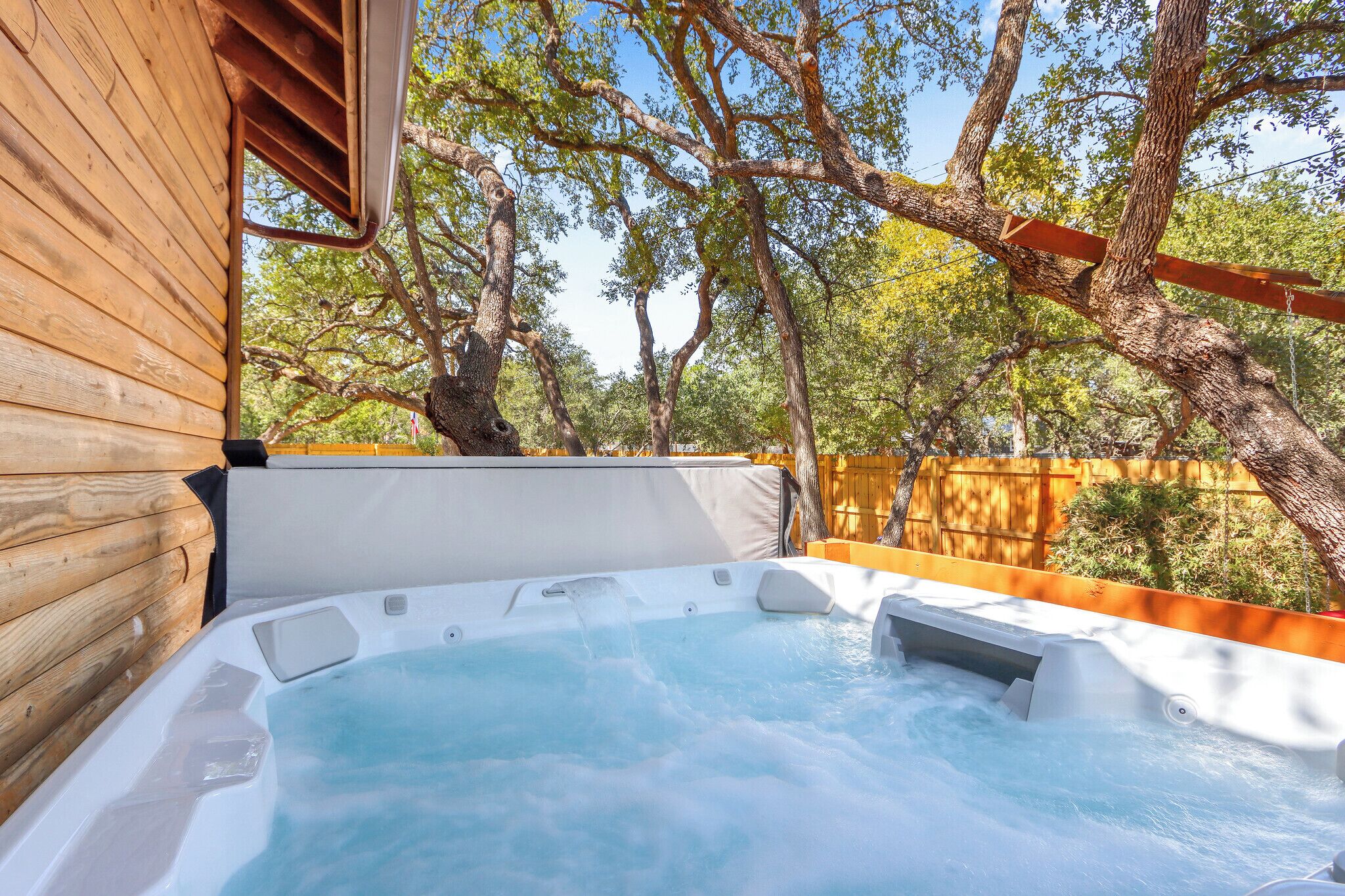 Un espace avec un bain à remous, une terrasse en bois et une vue sur les arbres.