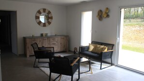 A modern living room with a sofa, two chairs, a coffee table, a wooden cabinet, and a large mirror on the wall.