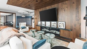 Ein modernes Wohnzimmer mit Kamin, Wand-Fernseher und gerahmten Kunstwerken an der Wand.