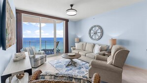 A spacious balcony with a view of the ocean, furnished with a sofa, armchairs, and a dining table.
