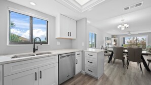 Une cuisine moderne avec des meubles blancs, un lave-vaisselle et un coin repas comprenant une table et des chaises.