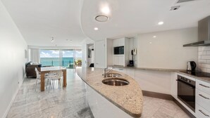 Una cocina moderna con encimera de granito, pileta de acero inoxidable y vista al océano.