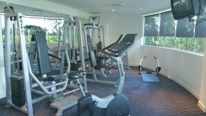Un gimnasio con diverso equipo de ejercicio, que incluye una cinta de correr, máquinas de pesas y una máquina de remo.
