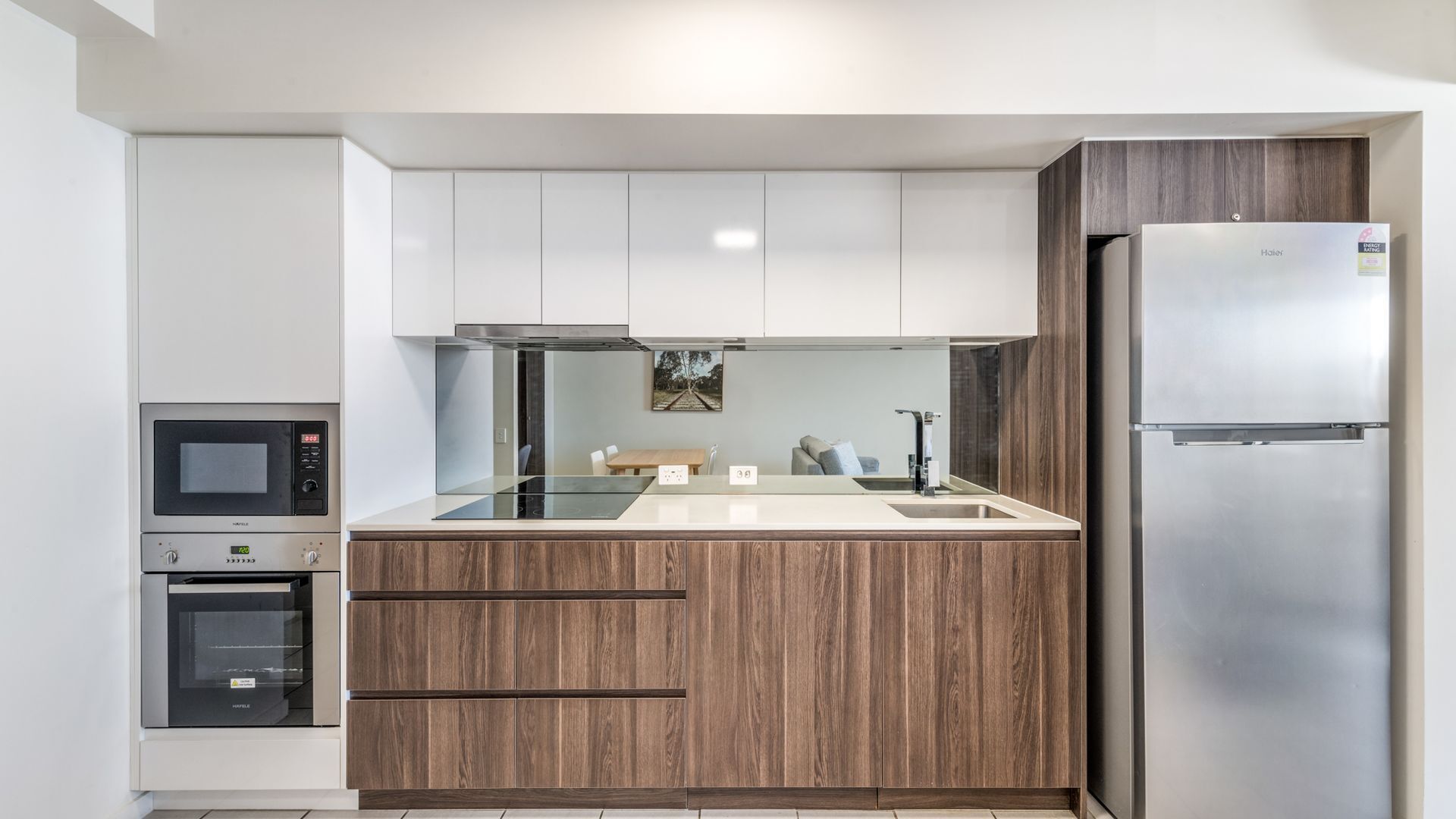 A modern kitchen with a built-in oven, microwave, and refrigerator.