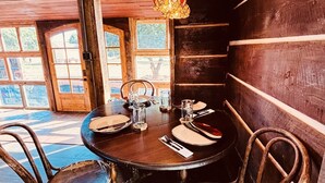 Een rustieke eethoek met een houten tafel gedekt voor vier personen, omringd door antieke stoelen.