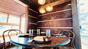 Een houten interieur met een ronde eettafel, compleet met borden, glazen en bestek.