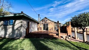 Een houten chalet met een veranda, een garage en een omheind erf.