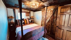 Een landelijke slaapkamer met een hemelbed, houten wanden en een grote houten deur.