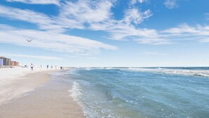 A beach with clear skies, gentle waves, and a few people walking along the shore. - 4BR Beachfront, Lazy River w/ Slide, New to Market!! (Orange Beach)