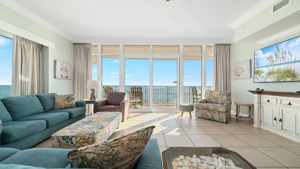 A spacious living room with a large sliding glass door leading to a balcony overlooking the ocean. - 4BR Beachfront, Lazy River w/ Slide, New to Market!! (Orange Beach)